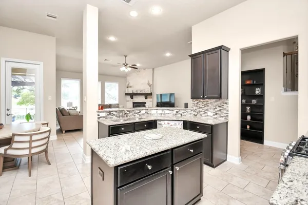 a kitchen with granite countertop kitchen island stainless steel appliances a sink stove and cabinets