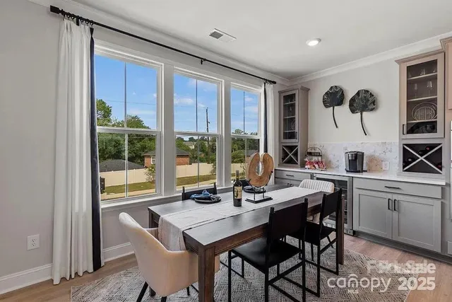 a kitchen with stainless steel appliances kitchen island granite countertop a table chairs stove and white cabinets