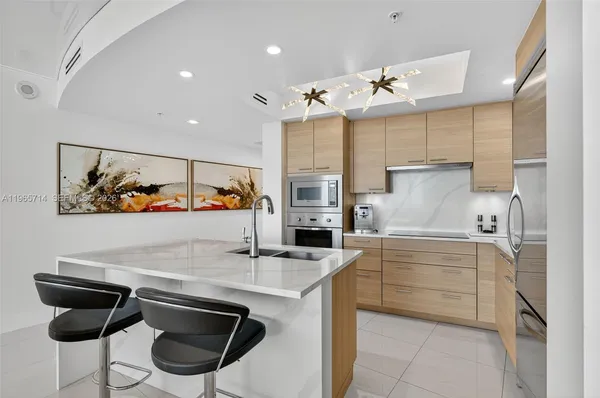 a kitchen with stainless steel appliances kitchen island granite countertop a refrigerator and a sink