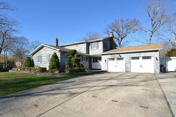 a front view of a house with a garden and trees