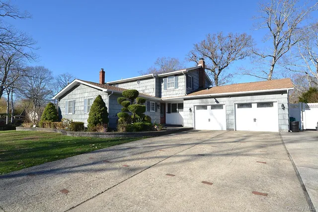 a front view of a house with a garden and trees