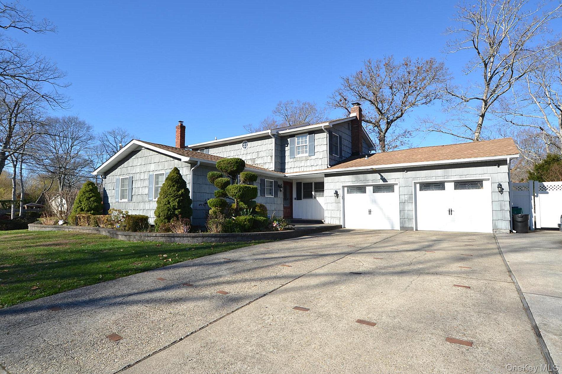 a front view of a house with a garden and trees