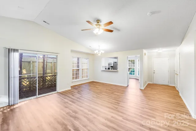 a view of an empty room with window and wooden floor