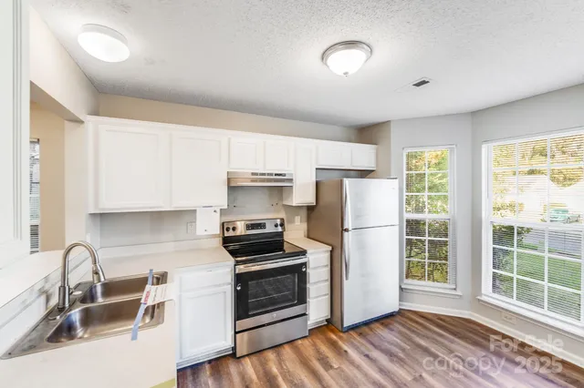 a kitchen with stainless steel appliances a stove a sink a refrigerator cabinets and a window