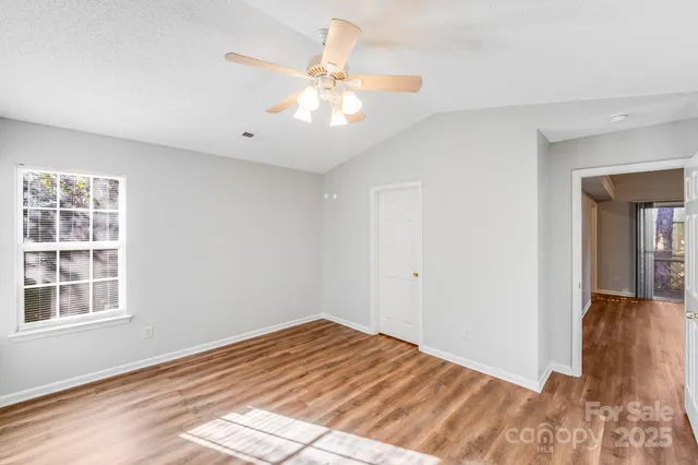 a view of empty room with wooden floor and fan