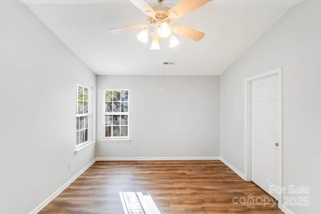 a view of an empty room with window and wooden floor
