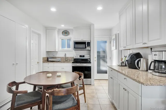 a kitchen with stainless steel appliances granite countertop a sink a stove a refrigerator cabinets and a dining table with wooden floor