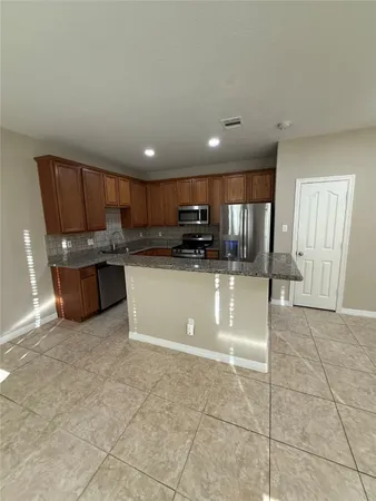 a large kitchen with a large counter top stainless steel appliances and cabinets