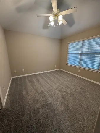 an empty room with a chandelier fan and windows