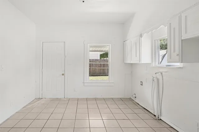a view of an empty room with window and cabinet area
