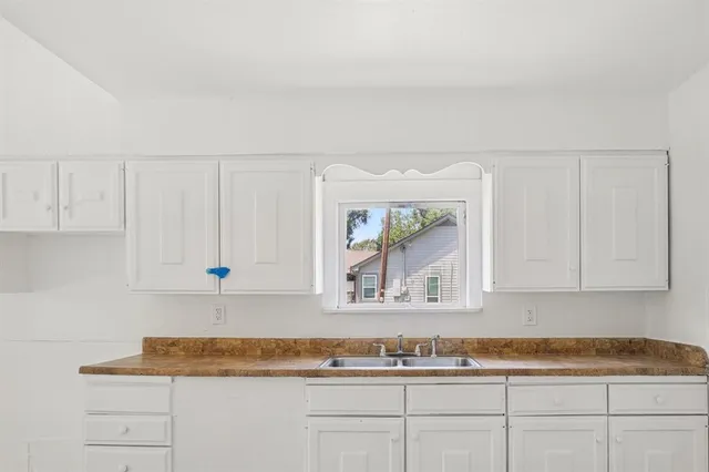 a kitchen with granite countertop white cabinets and a sink