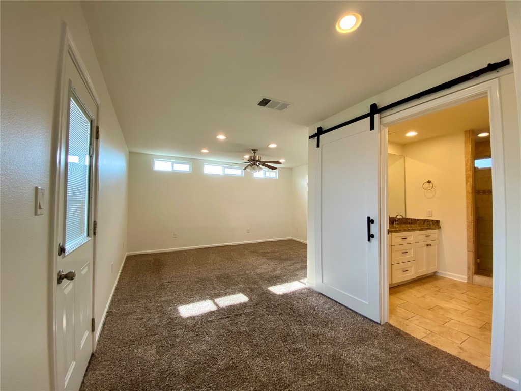 2003 Patton Lane Austin, TX 78723 - Photo 12 of 38 Primary bedroom featuring light carpet, a barn door, recessed lighting, and connected bathroom
