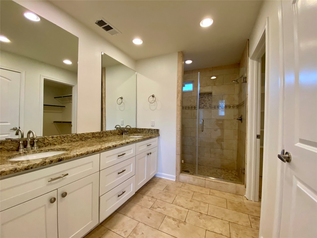 2003 Patton Lane Austin, TX 78723 - Photo 14 of 38 Full bathroom featuring double vanity, a gorgeous shower, recessed lighting, a spacious closet, and light tile patterned floors