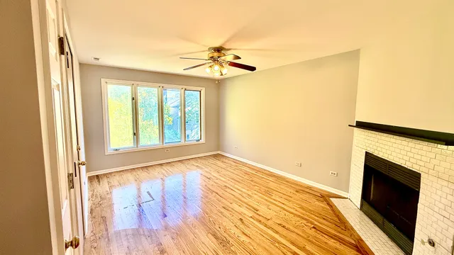 a view of an empty room with wooden floor fireplace and a window