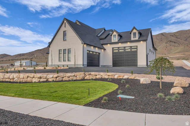 2828 Jojo Road Eagle Mountain, UT 84005 - Photo 4 of 63 White facade architecture featuring multiple dormer windows, a dark shingle roof, and dark multi-pane garage doors