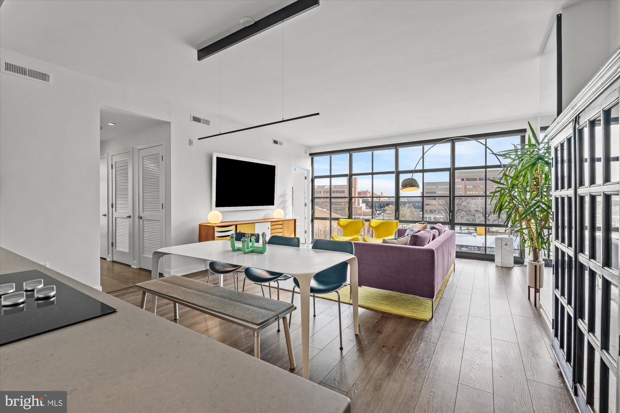 a living room with furniture floor to ceiling window and wooden floor