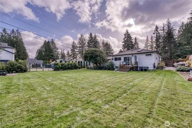 a view of a house with a big yard and large trees