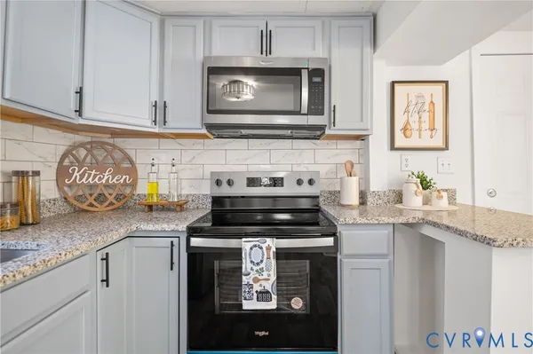 a kitchen with granite countertop a stove top oven microwave and cabinets