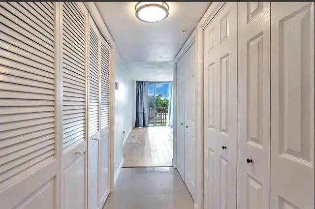 a view of a hallway with wooden floor and a bathroom