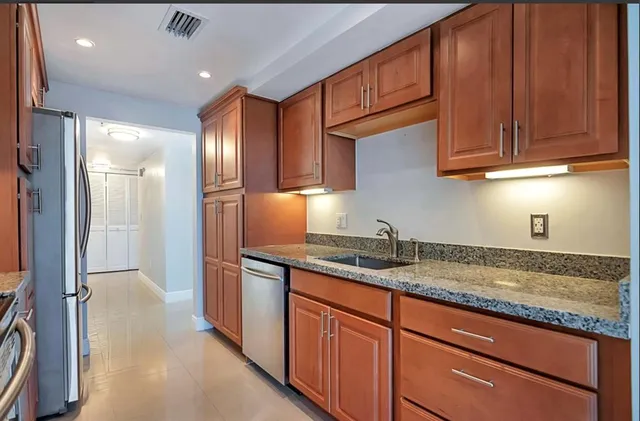 a kitchen with granite countertop stainless steel appliances a sink and cabinets
