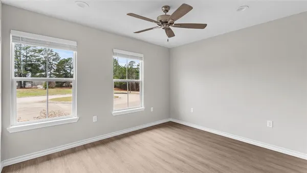 a view of an empty room with a window and wooden floor