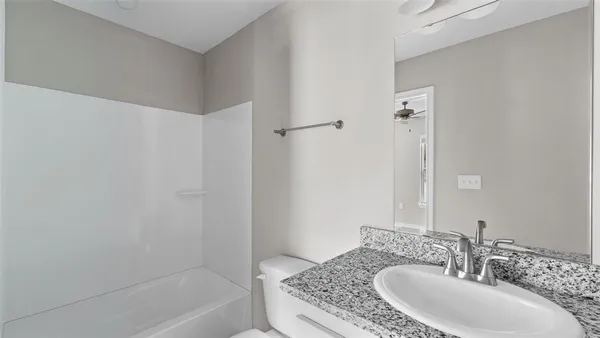 a bathroom with a granite countertop sink a mirror and a bathtub