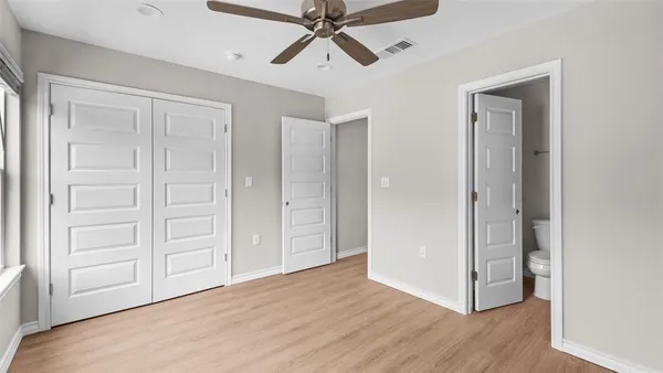 an empty room with wooden floor closet and windows