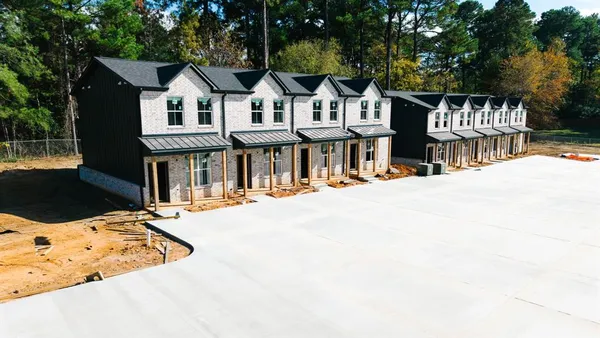 a view of a white house with a large tree and wooden fence