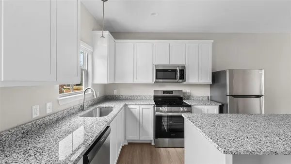 a kitchen with granite countertop a sink a stove and refrigerator