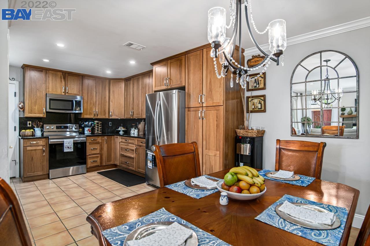 a kitchen with stainless steel appliances kitchen island granite countertop a refrigerator dining table and chairs