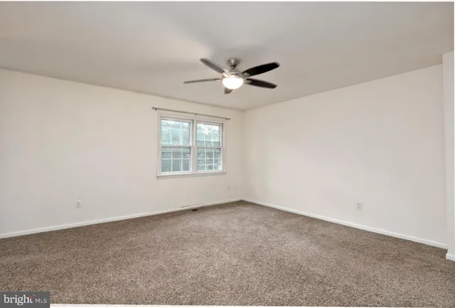 an empty room with a window and a ceiling fan