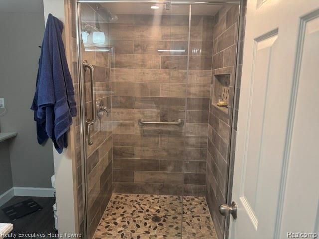 1467 Krafft Road, Unit 8 Port Huron, MI 48060 - Photo 27 of 28 Spacious shower enclosure with glass doors, wood-finish tile walls, pebble-style floor, and built-in grab bars