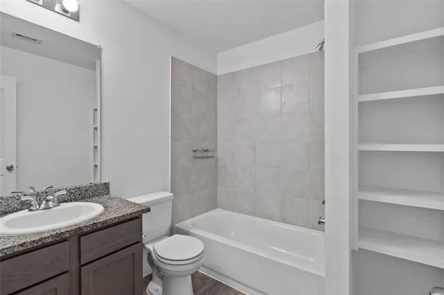 a bathroom with a granite countertop sink a toilet and shower