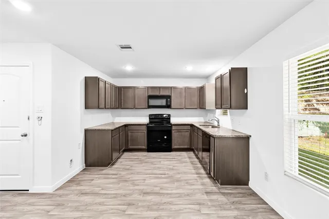 a large kitchen with a stove top oven a sink dishwasher a refrigerator and a microwave oven with wooden floor