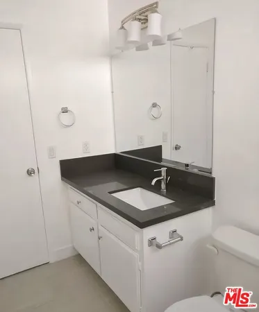 a bathroom with a granite countertop sink and a mirror