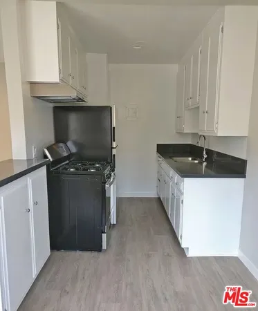 a kitchen with granite countertop white cabinets and black appliances