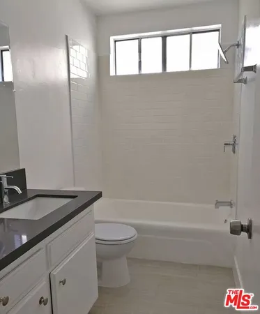 a bathroom with a granite countertop toilet a sink and bathtub