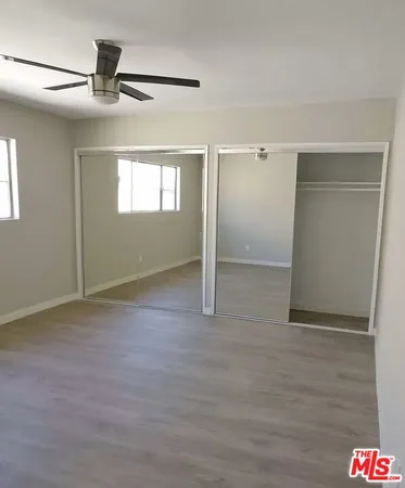 an empty room with windows and fan