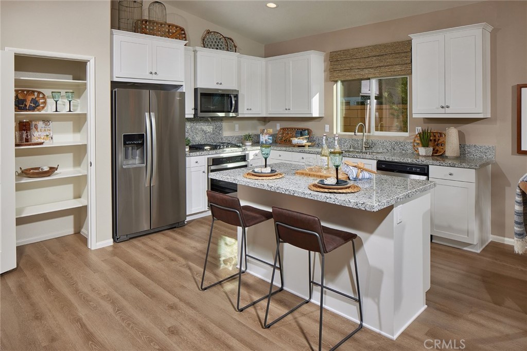 44376 Beringer Drive Indio, CA 92203 - Photo 6 of 17 a kitchen with stainless steel appliances granite countertop a stove a refrigerator a sink a stove and white cabinets with wooden floor