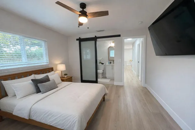 a spacious bedroom with a bed and a flat screen tv
