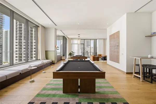 a living room with furniture a pool table and a large window
