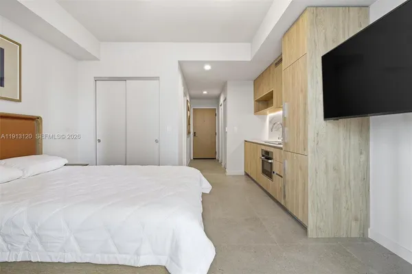 a spacious bedroom with a bed and a flat screen tv