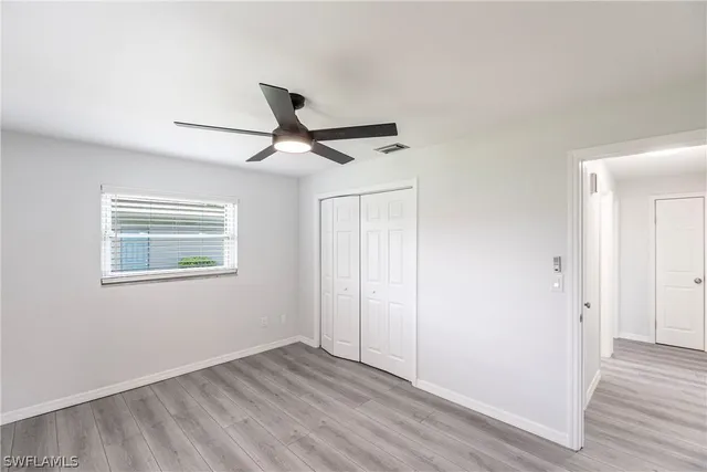 a view of an empty room with wooden floor and a ceiling fan