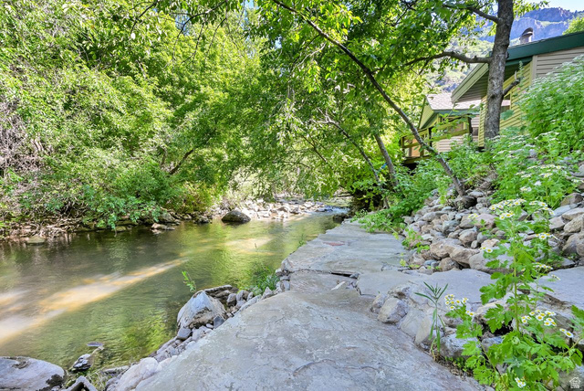 655 Ogden Canyon Road Ogden, UT 84401 - Photo 42 of 50 Riverfront property featuring a stone path, lush surrounding trees, and a distant house with a balcony