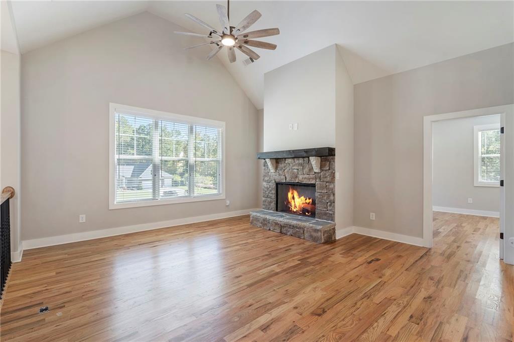 17 Pinoak Trail Cartersville, GA 30121 - Photo 4 of 37 an empty room with windows a fireplace a ceiling fan and wooden floor