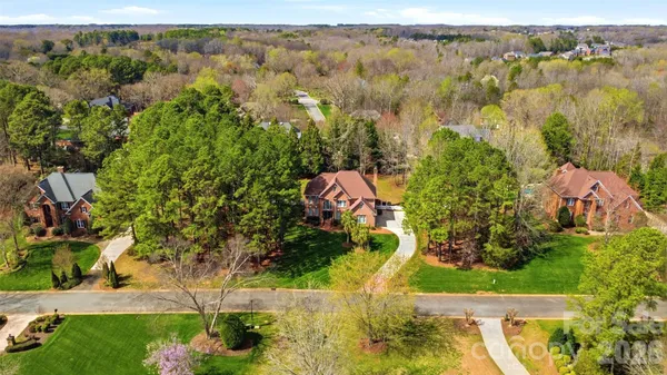 an aerial view of residential house with outdoor space and trees all around