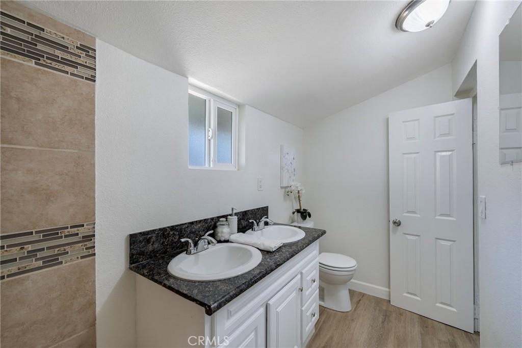 3751 McKenzie Street Riverside, CA 92503 - Photo 31 of 68 a bathroom with a granite countertop toilet a sink and a mirror