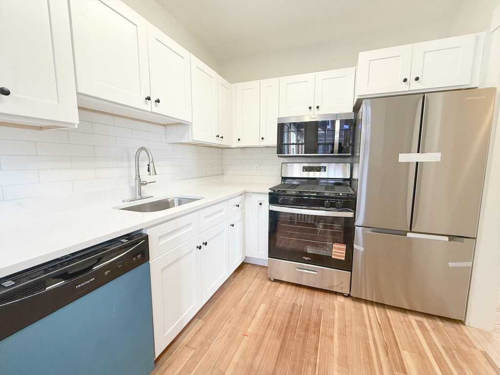 56 Selkirk Road, Unit 8 Boston, MA 02135 - Photo 5 of 8 a kitchen with a refrigerator and white cabinets