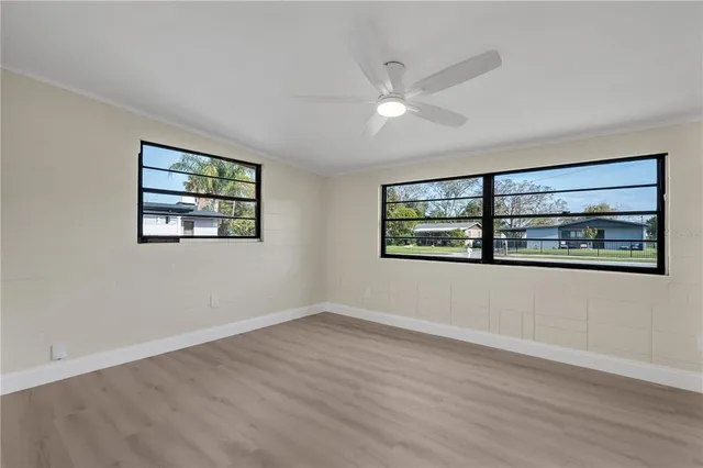 a view of an empty room with window and wooden floor