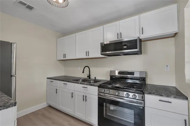 a kitchen with stainless steel appliances granite countertop grey cabinets a stove a sink and dishwasher